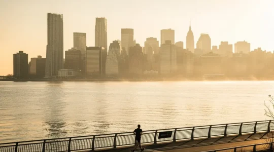Un coureur matinal longeant la Hudson River Greenway avec la skyline de Manhattan en arrière-plan au lever du soleil